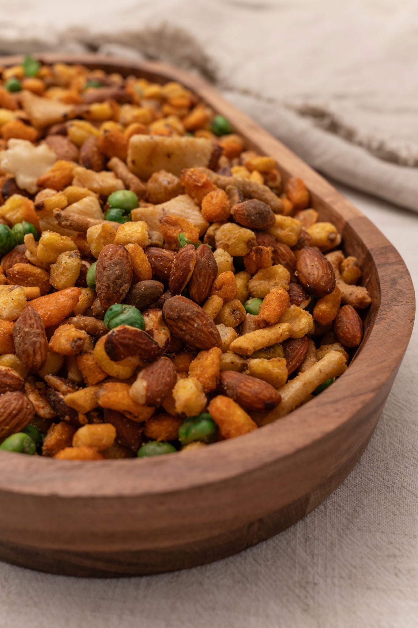 Wooden bowl filled with assorted nuts, corn and rice crackers