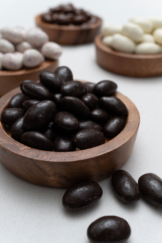 Wooden bowl filled with dark chocolate covered almonds