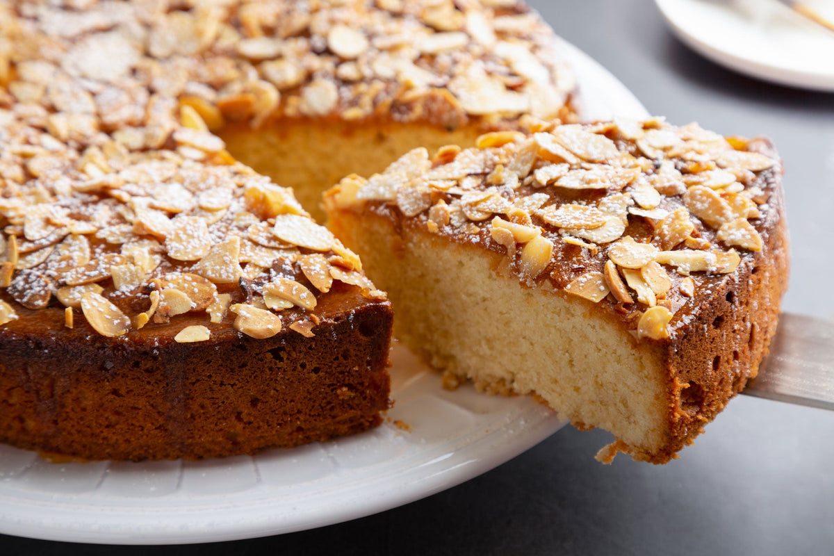 Slice of almond cake being moved from the main cake