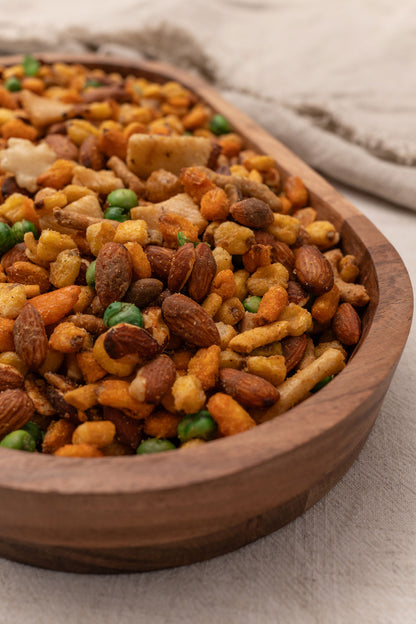 Wooden bowl filled with assorted nuts, corn and rice crackers