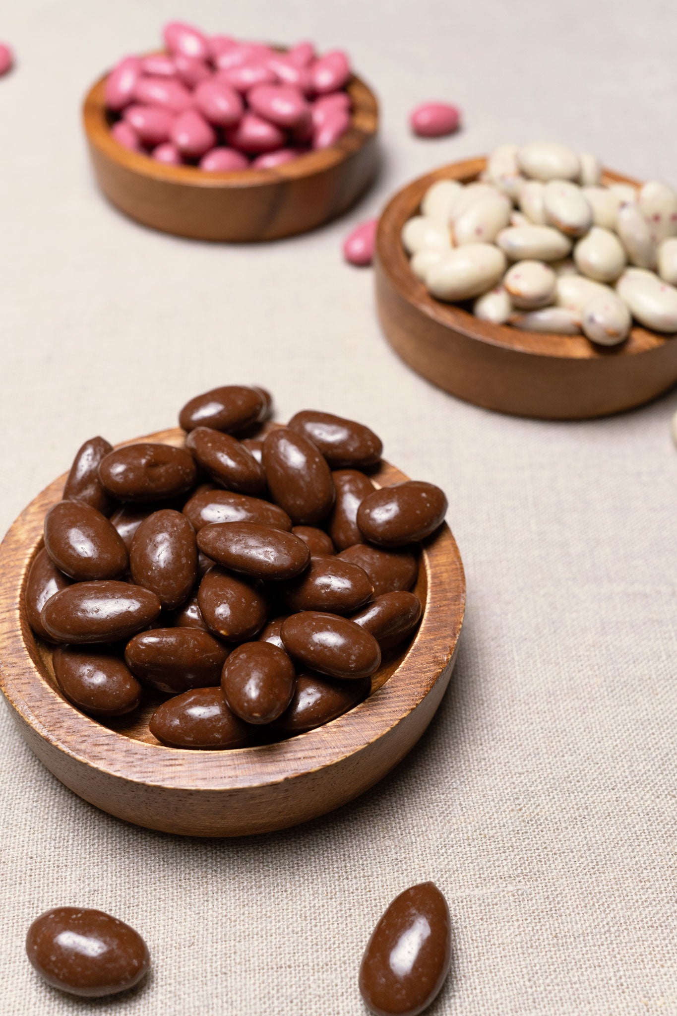 Wooden bowl filled with almonds covered in chocolate caramel with sea salt