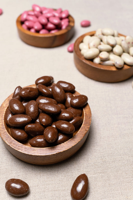 Wooden bowl filled with almonds covered in chocolate caramel with sea salt
