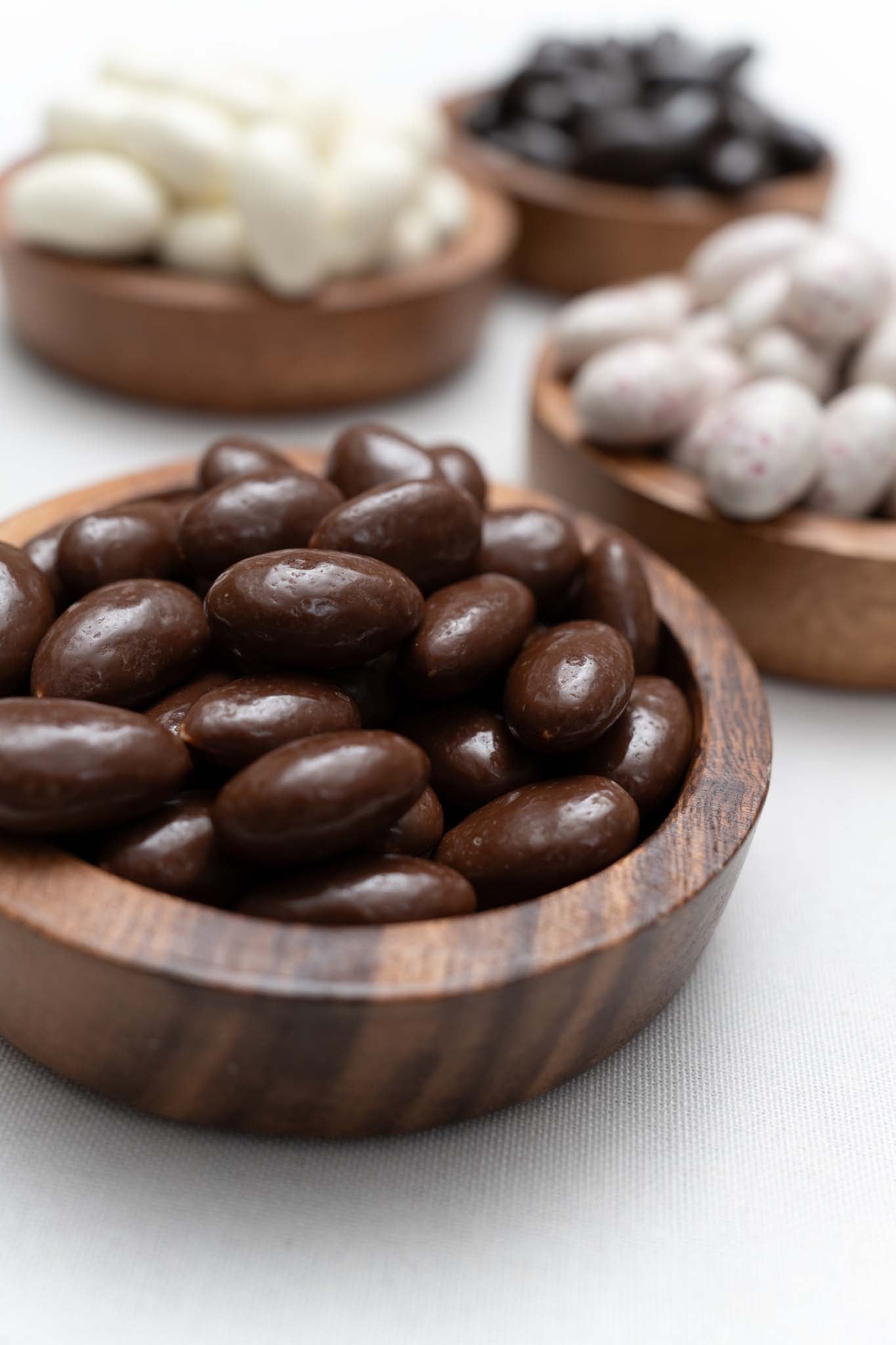 Wooden bowl filled with milk chocolate covered almonds