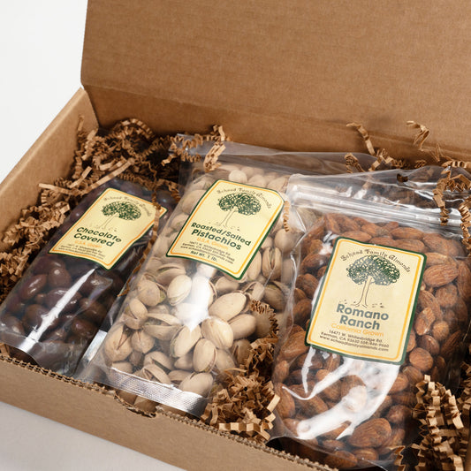 Three bags of nuts in a cardboard box with decorative paper.