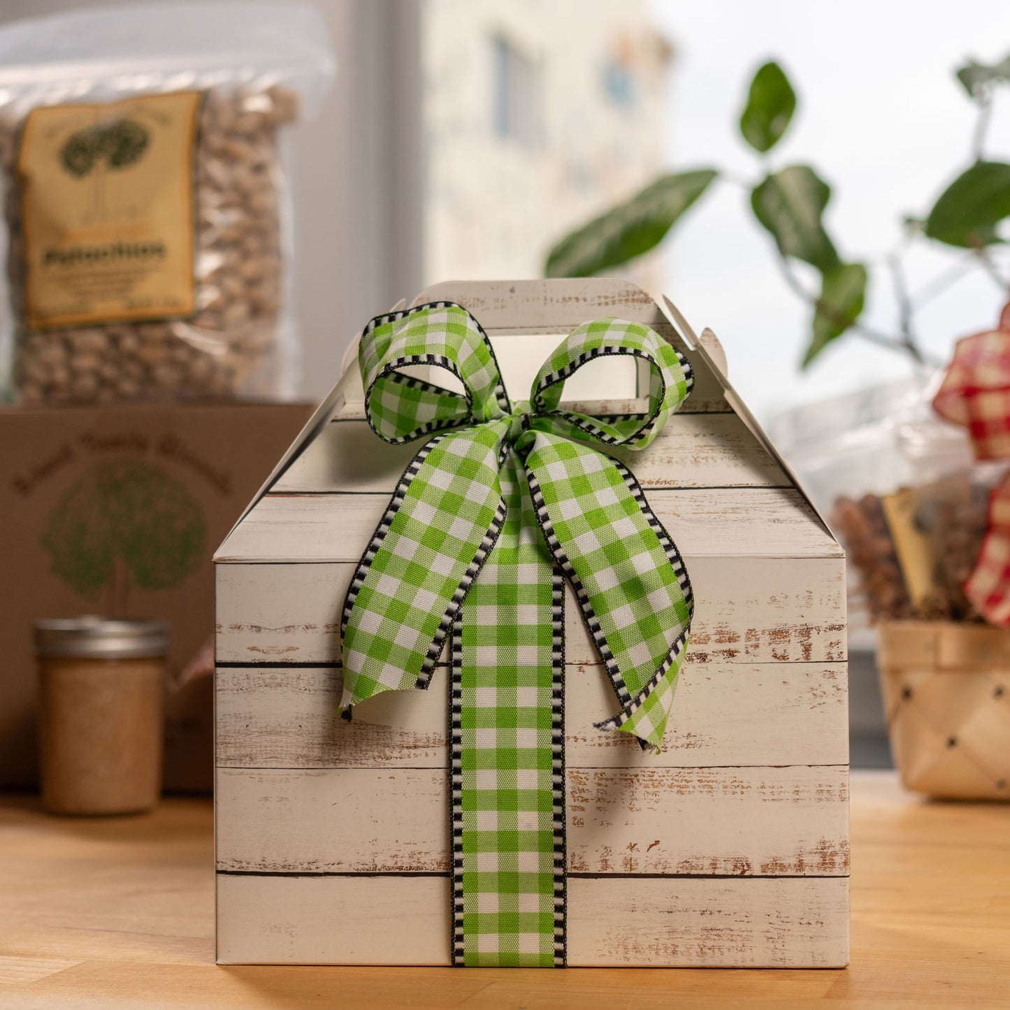 Cardboard box with a green bow with various nut products in the background