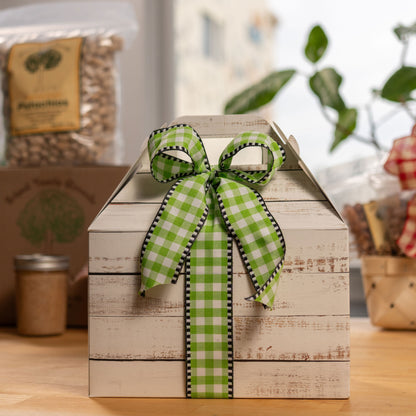 Cardboard box with a green bow with various nut products in the background