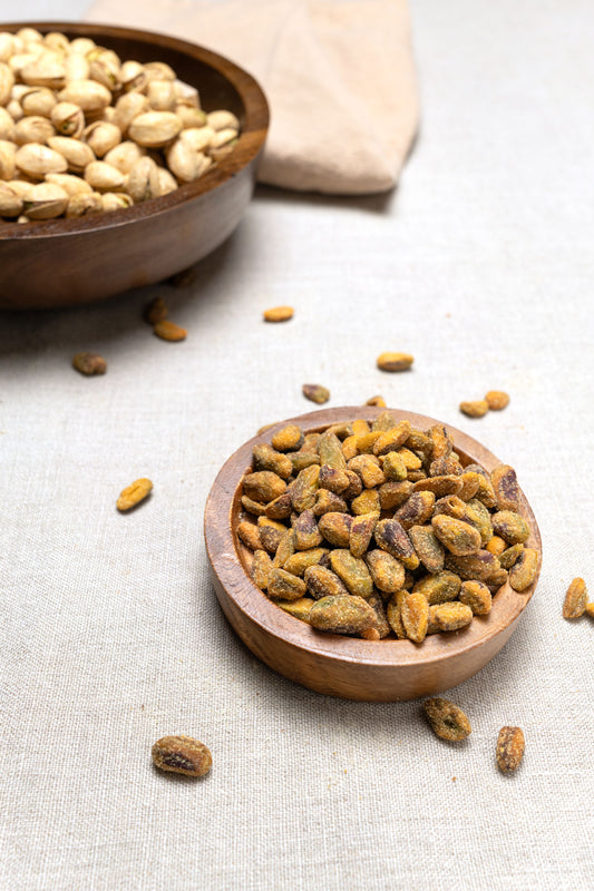 Wooden bowl filled with unshelled chili roasted pistachios