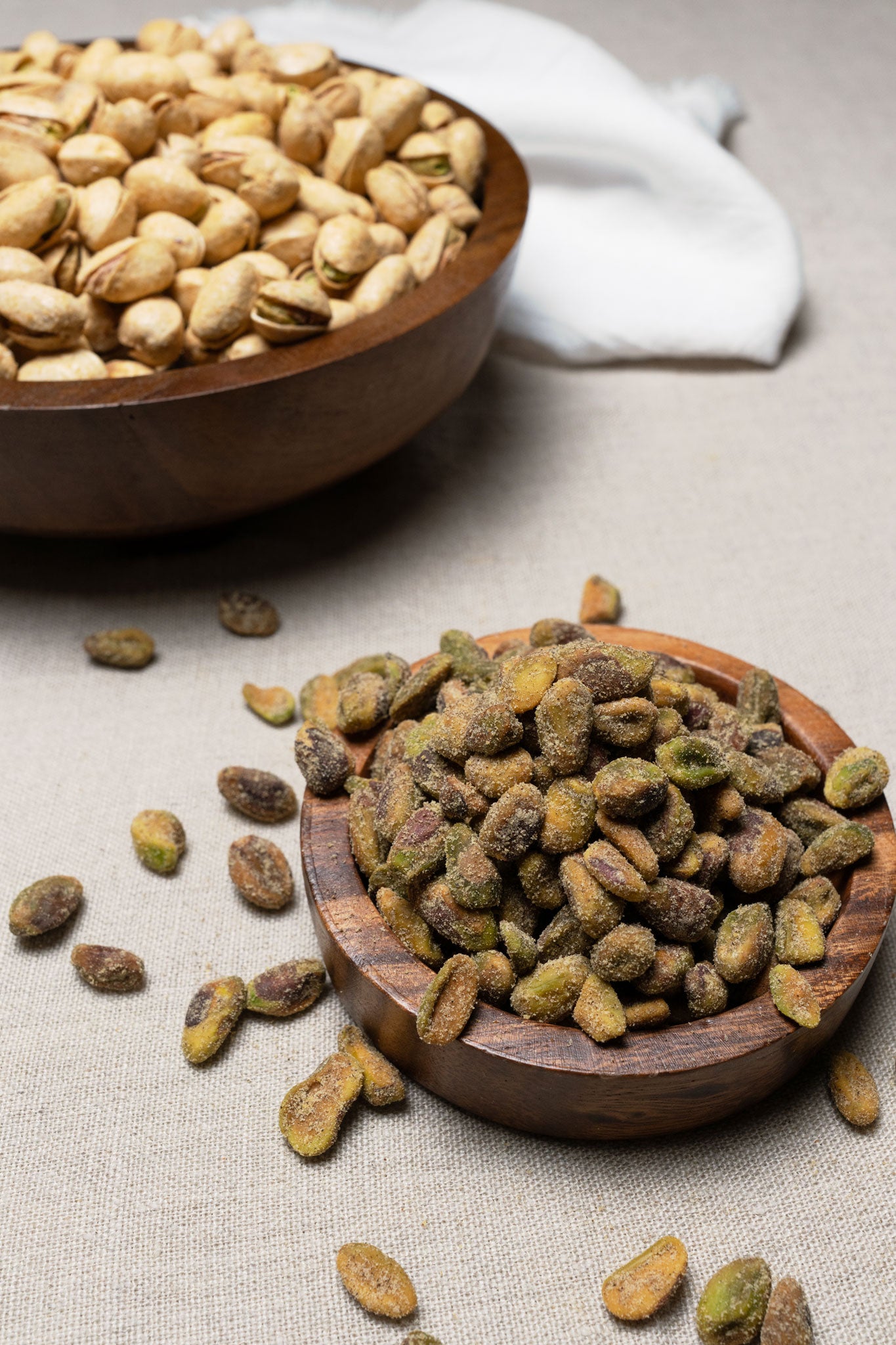 Wooden bowl filled with unshelled pistachios seasoned with salt and pepper